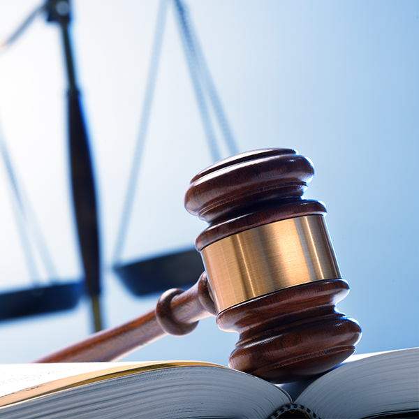 Gavel on book with scales of justice behind it.