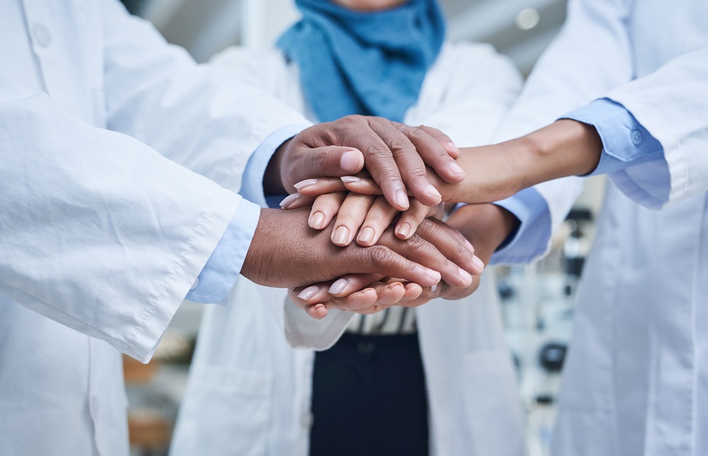 doctors huddling with hands on top of hands